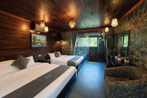 a hotel room with two beds and a chair at Trang An Mountain River Ecolodge in Ninh Binh