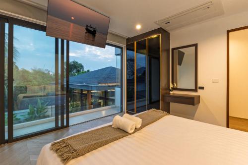 a bedroom with a large bed and large windows at Luxe & Privacy Orchard Villas Pasak 4BR in Laguna Phuket