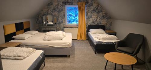 a room with three beds and a chair and a window at Rancho U Bodzia in Jeleniów