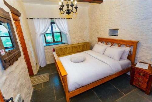 a bedroom with a bed with white sheets and a window at SAUNTON GRANGE 7 Bedrooms in Braunton
