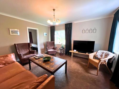 a living room with a couch and a tv at Finnsstaðir Holiday Home with Hot tub in Egilsstaðir