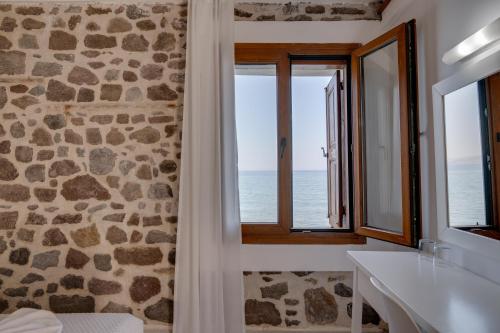 a bathroom with a stone wall and a window at Olive Press Hotel in Mythimna
