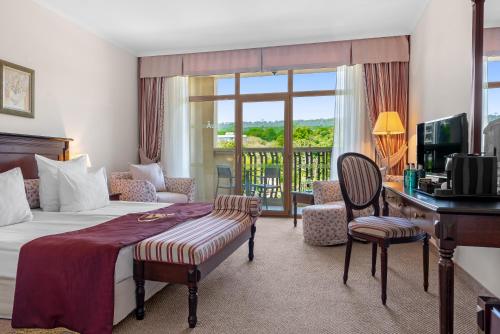 a hotel room with a bed and a desk and a balcony at Meliá Grand Hermitage All Inclusive in Golden Sands