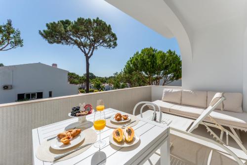 a table with food and wine glasses on a balcony at Vale Do Lobo Resort in Vale do Lobo
