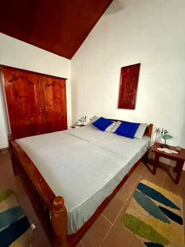 a bedroom with a large bed with blue pillows at Dara Place in Dickwella