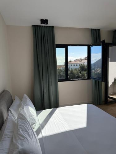 a bedroom with a bed and two windows at Pauz Hotel in Himare