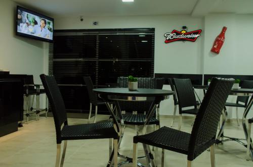 a dining room with a table and chairs and a screen at Hollyster Hotel in Curitiba
