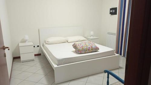 a white bedroom with a bed with a pillow on it at La terrazza sul mare in Messina
