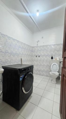 a bathroom with a toilet and a washing machine at palm ridge apartment Diani beach in Diani Beach