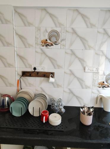 a counter with plates and bowls on a table at Blue Door Homes in Navi Mumbai