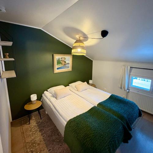 a bedroom with a large bed with a green wall at Korpinpesä in Korppoo