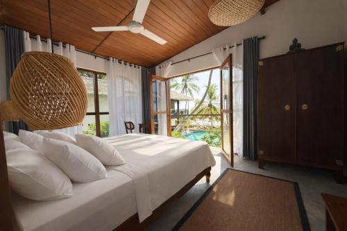 a bedroom with a large bed with white pillows at South Coast Villas by Mandala in Tangalle