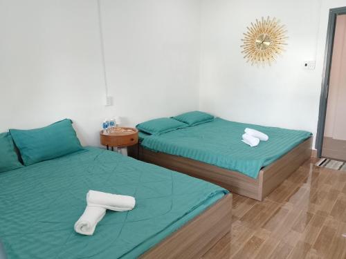 two beds in a room with green sheets and towels at Hom Ba cây dừa in Vĩnh Hy