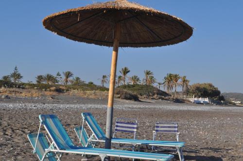 two lounge chairs and an umbrella on a beach at Villa Imerti Kiotari in Kiotari