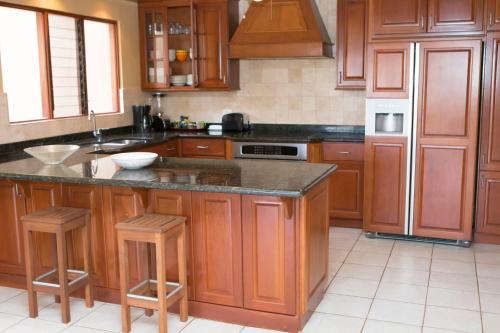 a kitchen with wooden cabinets and a island with stools at Bahia Pez Vela Resort in Ocotal