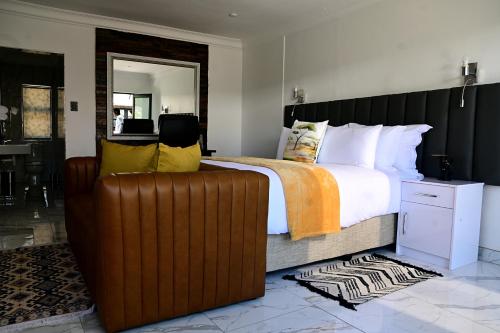 a bedroom with a large bed and a brown leather couch at His Grace Eagles Guesthouse in Bloemfontein
