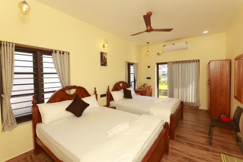 a bedroom with two beds and a ceiling fan at Coastal Calm Inn in Fort Kochi
