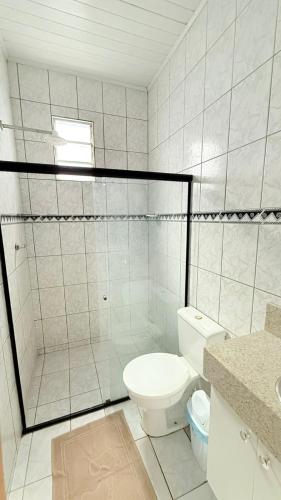 a white bathroom with a toilet and a shower at Chácara das Mangueiras in Aracaju