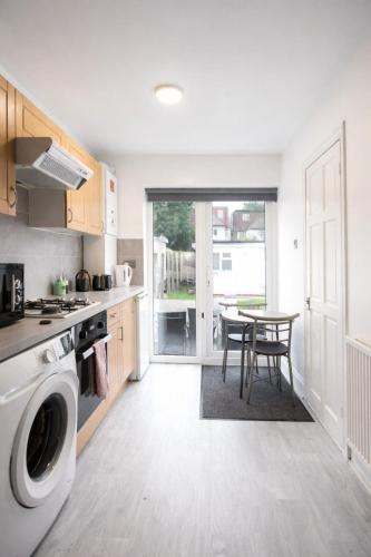a kitchen with a washing machine and a table at Large Studio Garden Flat on Golders Green Road in London