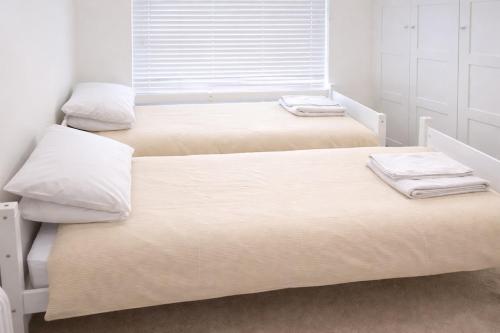 three beds in a room with white walls at Beautiful Flat 2-Mins away from Rochester Station in Rochester