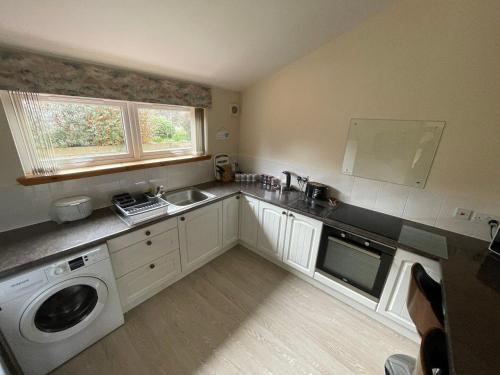 a kitchen with a sink and a washing machine at Hopeman Cottage in Hopeman