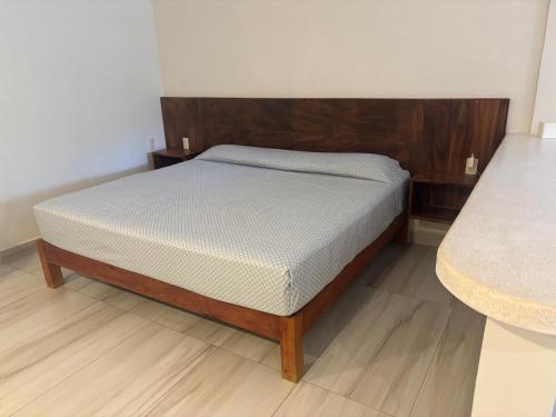 a bed with a wooden headboard in a room at Apartamentos mondala in Brisas de Zicatela