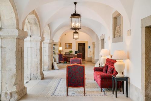 a living room with red chairs and a chandelier at Pousada Castelo de Palmela in Palmela
