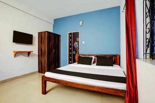 a bedroom with a bed with a blue wall at Hotel O Kunal guest house in Goa