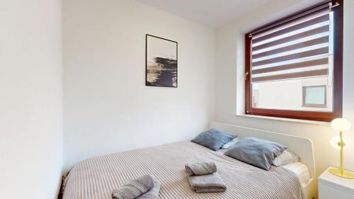 a bedroom with a bed with two pillows and a window at Apartament Fibra Cortado in Rybnik