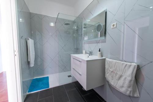a white bathroom with a shower and a sink at Apartamentos Amarelo in Caniçal