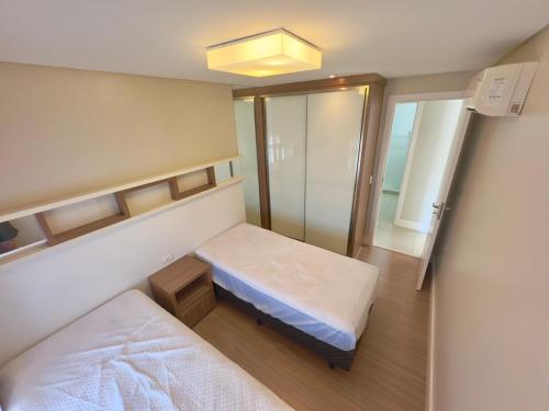 a hospital room with two beds and a mirror at Excelente Apto no condomínio Boulevard in Bombinhas