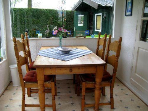 a wooden table with chairs and a vase of flowers on it at Apartment Haus Jule by Interhome in Wervershoof
