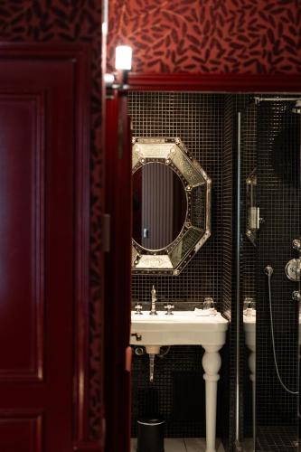 a bathroom with a sink and a mirror at Hôtel du Petit Moulin, Haute Couture hotel by Lacroix in Paris