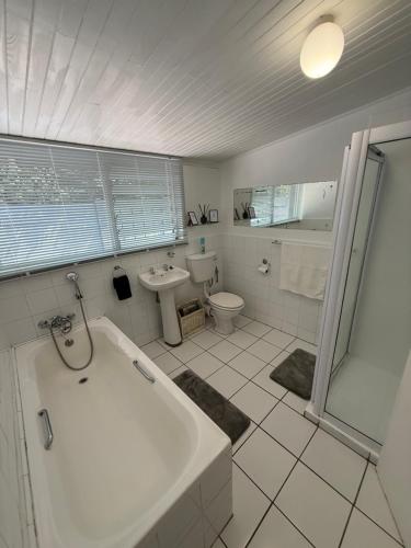 a bathroom with a tub and a toilet and a sink at The Garden Den in Nelspruit