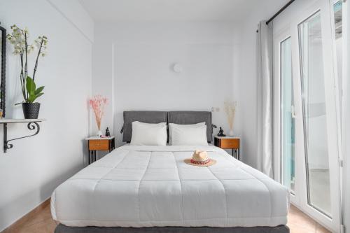 a white bedroom with a bed with a hat on it at Ornos Apartments in Ornos