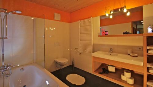 a bathroom with a tub and a toilet and a sink at Villa Natur in Schröcken