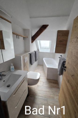 a bathroom with a sink and a toilet and a tub at Ferienwohnung NR4 DG Klima in Großräschen