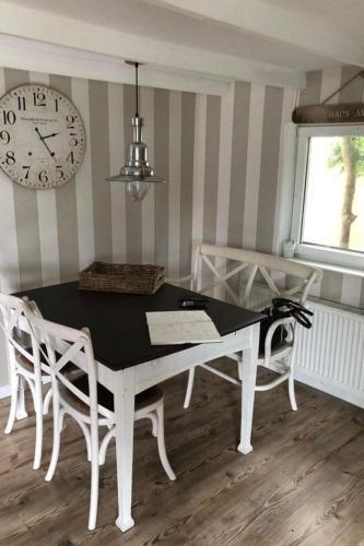 a dining room with a table and chairs and a clock at Apartment Tami by Interhome in Wervershoof