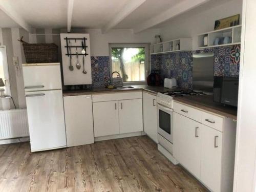 a kitchen with white appliances and a wooden floor at Apartment Tami by Interhome in Wervershoof