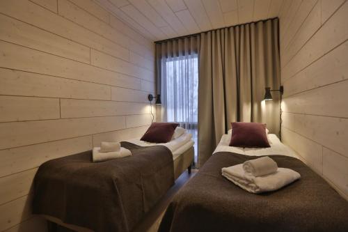 two beds in a room with wooden walls at Riekko Lodge in Äkäslompolo