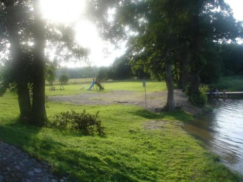 a park with a playground with trees and water at Apartment by Interhome in Łukta