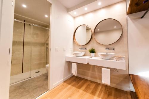 a bathroom with two sinks and two mirrors at El Mirador Del Alcazar in Segovia