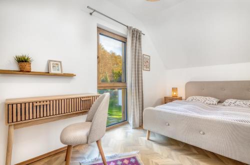 a bedroom with a bed and a window and a chair at Domki SOSNOWY PARK in Białogóra