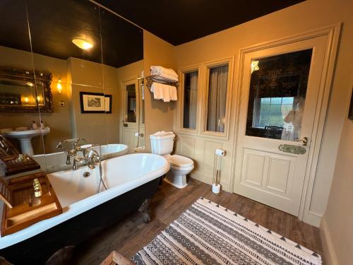 a bathroom with a tub and a toilet and a sink at Meifod country house hotel in Caernarfon