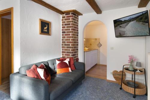 a living room with a gray couch and a brick wall at Bergleuchten -403- in Krün