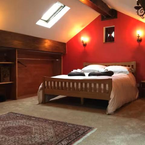 a bedroom with a bed with a red wall at Artie's Lodge in Windermere