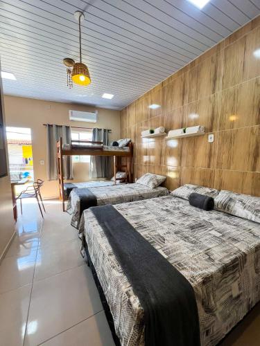 two beds in a room with wooden walls at Apartamento juçara Lençóis in Barreirinhas