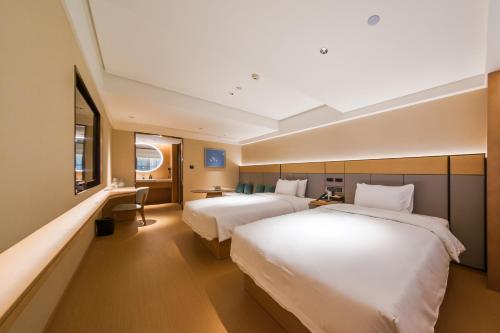 a hotel room with two beds and a desk at JI Hotel Beijing Station in Beijing