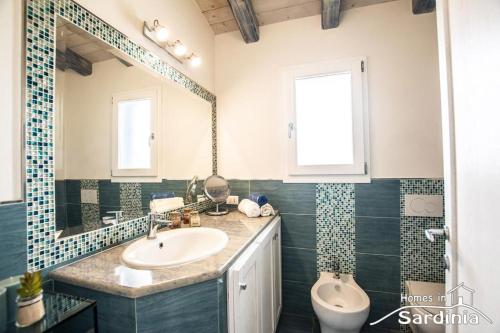 a bathroom with a sink and a mirror and a toilet at Tra blu e celeste in Castelsardo