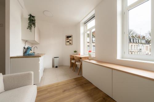 a white kitchen with a counter and a table at Le Cocoon Studio 2 voyageurs in Arras